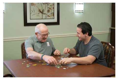Elderly gentleman working on a puzzle with his grandson